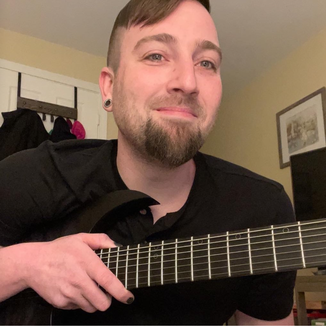 Photo of Bryan Moyer smiling and holding a guitar neck